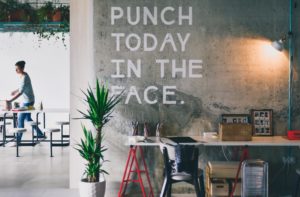 Office trend in 2020. Office space with hanging plants in background and plants next to a desk.